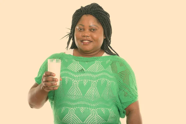 Estudio disparo de la grasa feliz mujer africana negro sonriendo mientras sostiene el vaso de leche — Foto de Stock