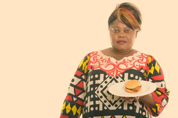 スタジオショットの脂肪黒アフリカ人女性保持ハンバーガー上のホワイトプレート — ストック写真