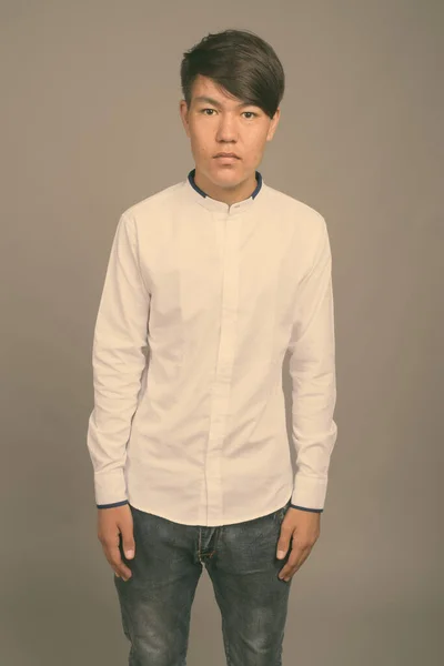Fiatal ázsiai tini fiú ellen szürke háttér — Stock Fotó