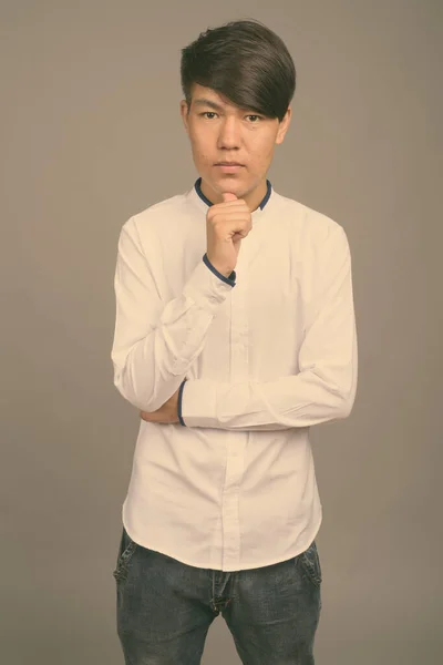 Ung asiatisk tonåring pojke mot grå bakgrund — Stockfoto