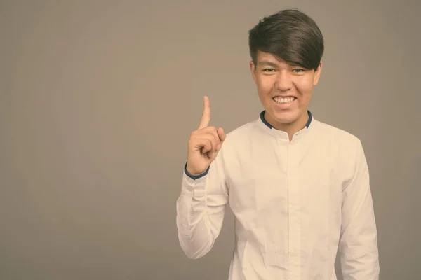 Joven asiático adolescente chico contra gris fondo —  Fotos de Stock