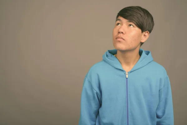 Giovane asiatico adolescente ragazzo contro grigio sfondo — Foto Stock