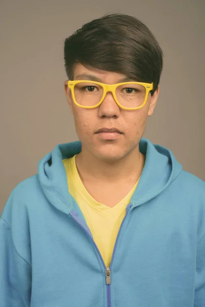 Joven asiático adolescente chico contra gris fondo —  Fotos de Stock