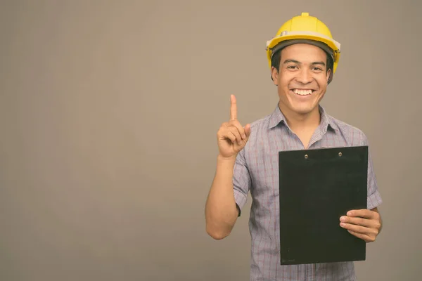 Ung asiatisk affärsman bär hatt mot grå bakgrund — Stockfoto