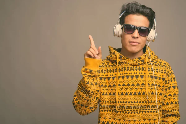 Joven asiático escuchando música sobre fondo gris —  Fotos de Stock