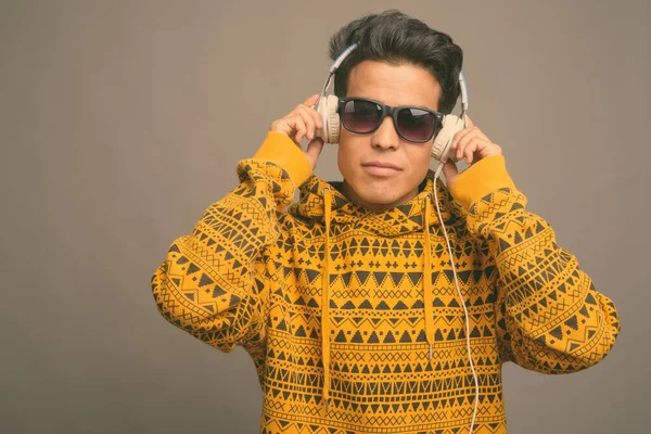 Junger Asiate hört Musik vor grauem Hintergrund — Stockfoto