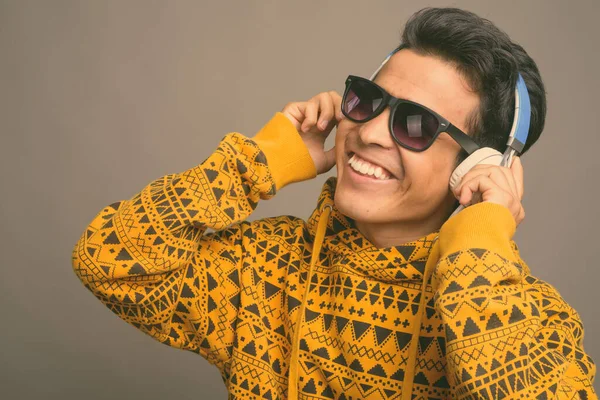 Молодой азиат слушает музыку на сером фоне — стоковое фото