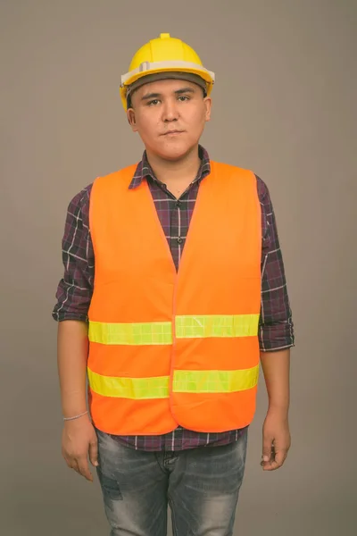 Joven asiático hombre construcción trabajador contra gris fondo —  Fotos de Stock