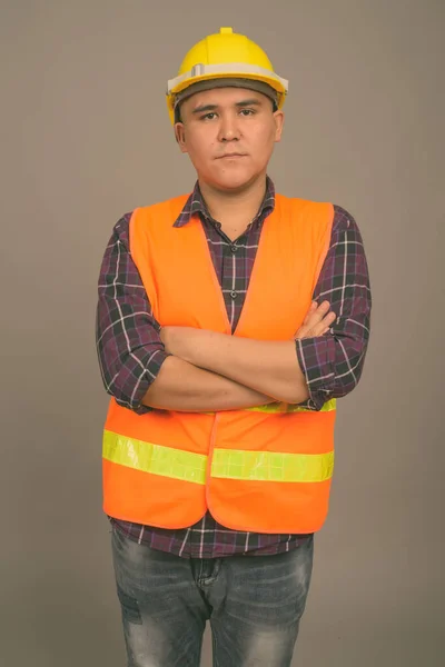 Молодий азіатський будівельник на сірому фоні — стокове фото
