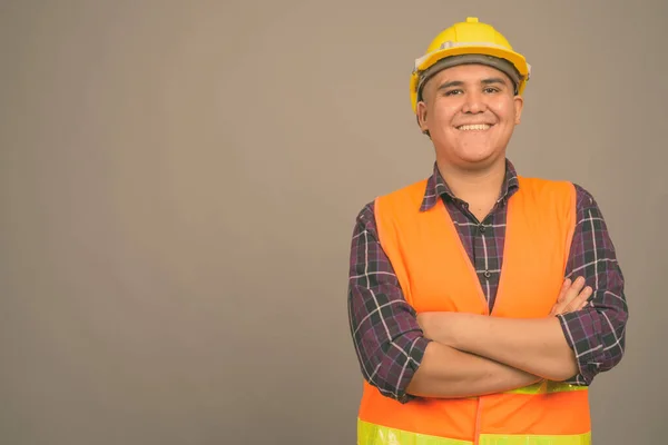 Jovem ásia homem construção trabalhador contra cinza fundo — Fotografia de Stock