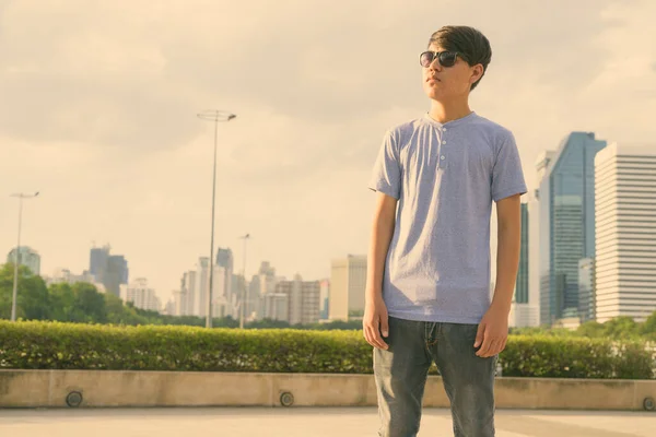 Jeune adolescent asiatique portant des lunettes de soleil tout en se relaxant au parc — Photo