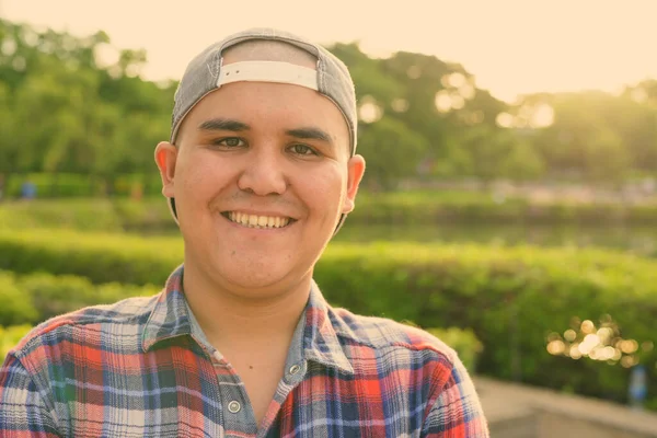 Junger asiatischer Mann mit Mütze beim Entspannen im Park in Bangkok, Thailand — Stockfoto