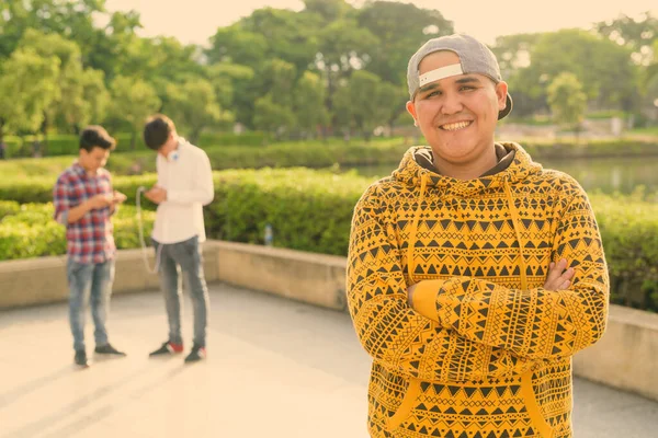 Tre unge asiatiske mænd slapper af i parken sammen - Stock-foto