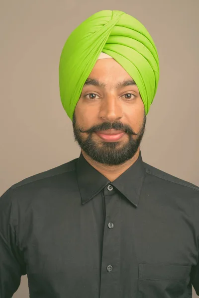 Fiatal jóképű indiai szikh üzletember visel turbánt szürke háttér — Stock Fotó