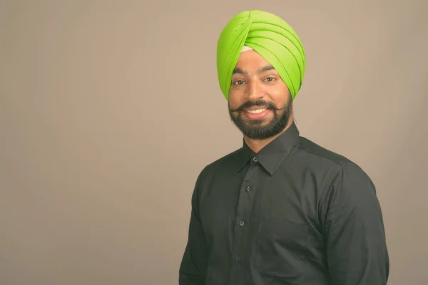 Jonge knappe Indiase Sikh zakenman met tulband tegen grijze achtergrond — Stockfoto