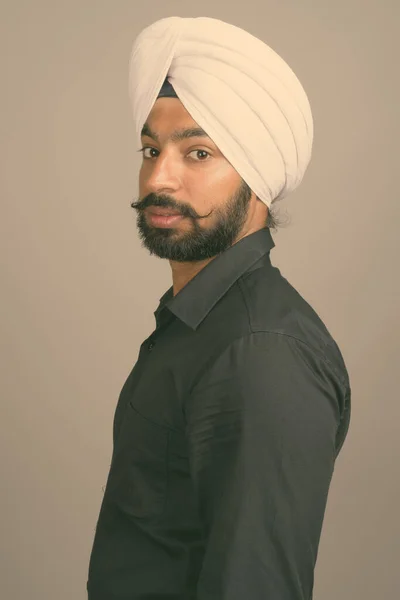 Joven hombre de negocios sikh indio guapo usando turbante contra fondo gris — Foto de Stock