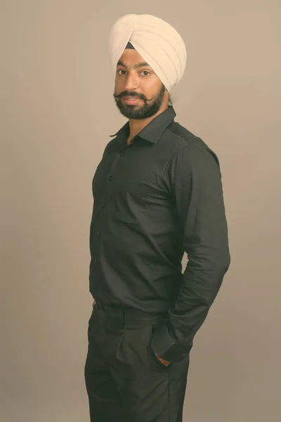 Joven hombre de negocios sikh indio guapo usando turbante contra fondo gris — Foto de Stock