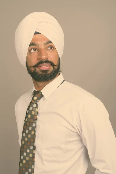 Giovane bell'uomo d'affari indiano Sikh indossa turbante contro sfondo grigio — Foto Stock