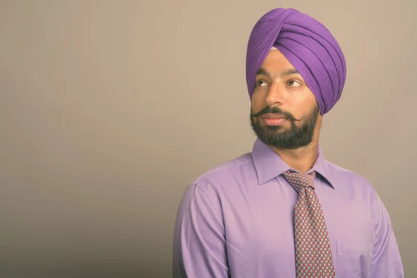 Jovem bonito indiano Sikh empresário vestindo turbante contra fundo cinza — Fotografia de Stock