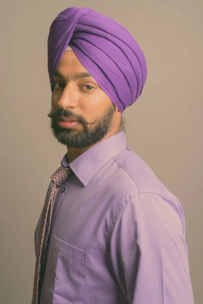 Ung stilig indisk sikh affärsman bär turban mot grå bakgrund — Stockfoto