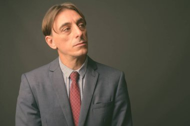 Olgun yakışıklı İtalyan işadamı gri arka planda