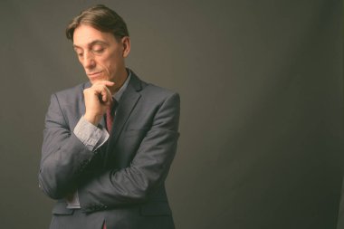 Olgun yakışıklı İtalyan işadamı gri arka planda