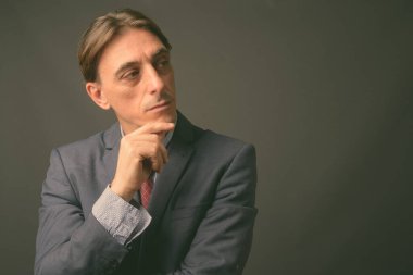Olgun yakışıklı İtalyan işadamı gri arka planda