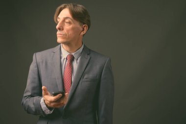 Olgun yakışıklı İtalyan işadamı gri arka planda