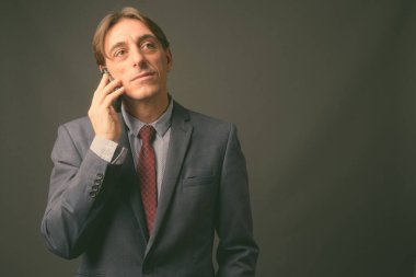 Olgun yakışıklı İtalyan işadamı gri arka planda
