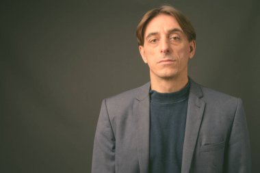Olgun yakışıklı İtalyan işadamı gri arka planda