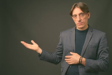 Olgun yakışıklı İtalyan işadamı gri arka planda
