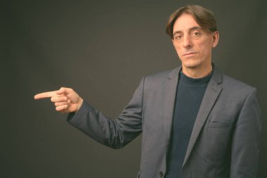 Olgun yakışıklı İtalyan işadamı gri arka planda