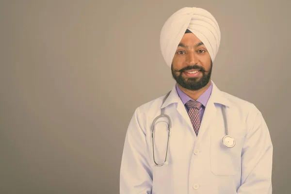 Jovem bonito indiano Sikh homem médico contra fundo cinza — Fotografia de Stock