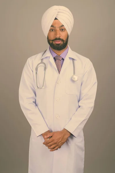 Jovem bonito indiano Sikh homem médico contra fundo cinza — Fotografia de Stock