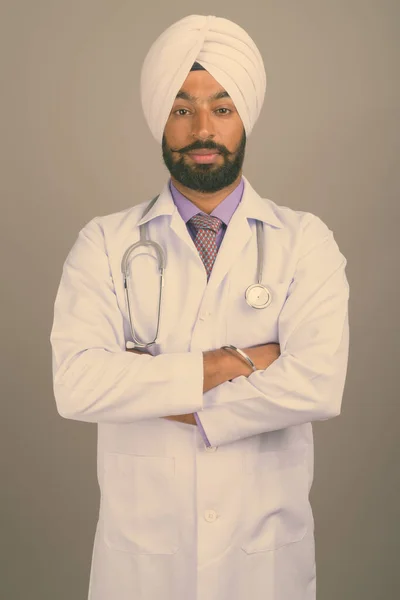 Jovem bonito indiano Sikh homem médico contra fundo cinza — Fotografia de Stock