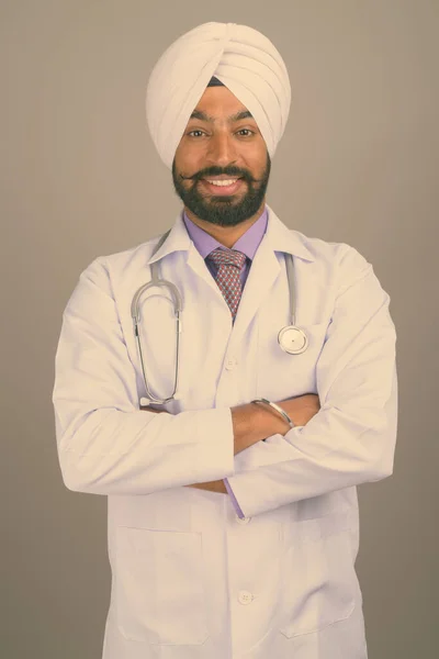 Fiatal jóképű indiai szikh férfi orvos szürke háttér — Stock Fotó