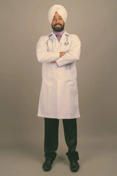 Joven guapo indio Sikh hombre médico sobre fondo gris — Foto de Stock