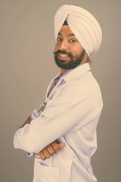 Jovem bonito indiano Sikh homem médico contra fundo cinza — Fotografia de Stock