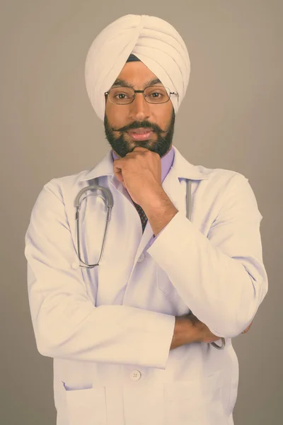 Jovem bonito indiano Sikh homem médico contra fundo cinza — Fotografia de Stock