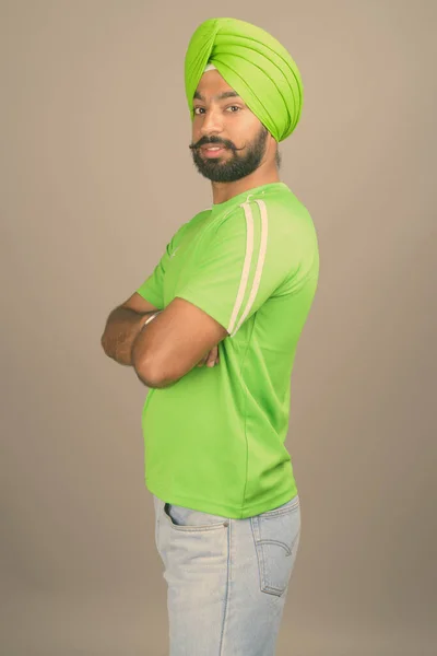 Ung vacker indisk sikh man bär turban mot grå bakgrund — Stockfoto