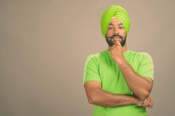 Ung vacker indisk sikh man bär turban mot grå bakgrund — Stockfoto