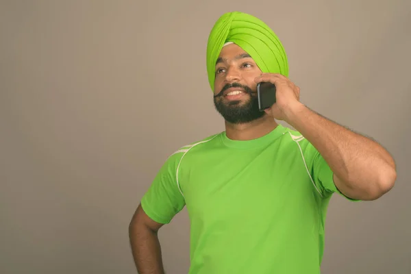 Young handsome Indian Sikh man wearing turban against gray background — Stock Photo, Image