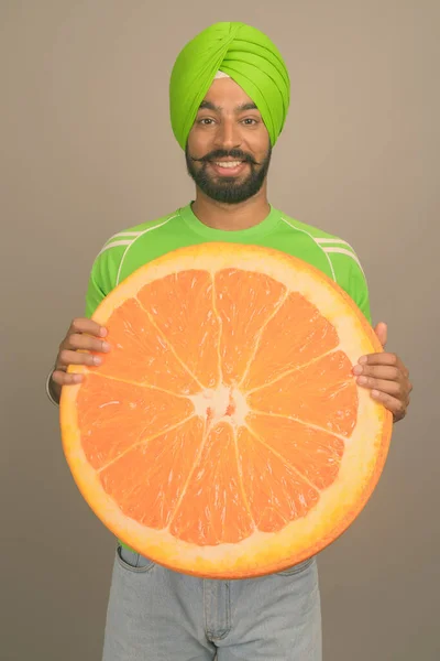 Joven hombre sikh indio guapo usando turbante contra fondo gris — Foto de Stock