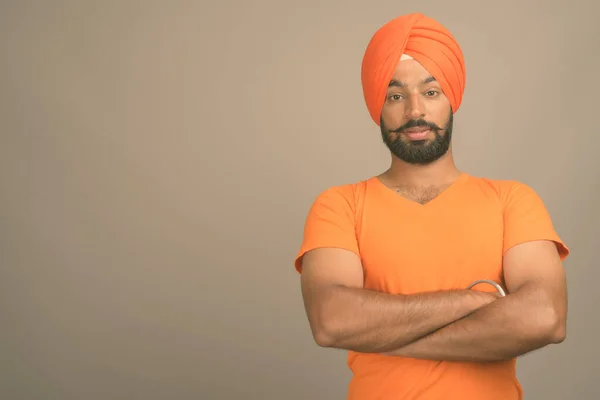 Jonge knappe Indiase Sikh man met tulband tegen grijze achtergrond — Stockfoto