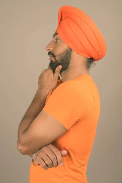 Mladý hezký indický sikh muž na sobě turban proti šedé pozadí — Stock fotografie