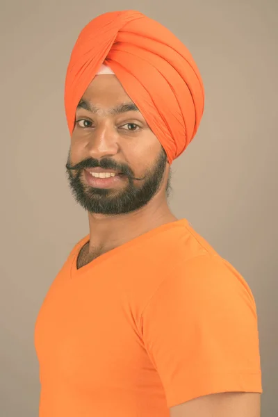 Ung vacker indisk sikh man bär turban mot grå bakgrund — Stockfoto