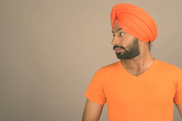 Jonge knappe Indiase Sikh man met tulband tegen grijze achtergrond — Stockfoto