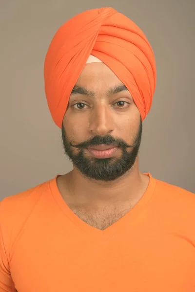 Ung vacker indisk sikh man bär turban mot grå bakgrund — Stockfoto