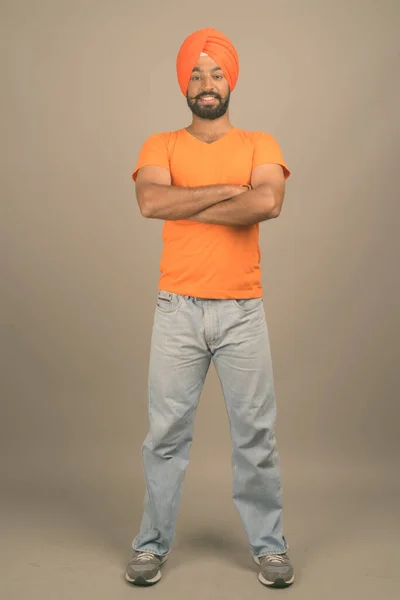 Joven hombre sikh indio guapo usando turbante contra fondo gris — Foto de Stock