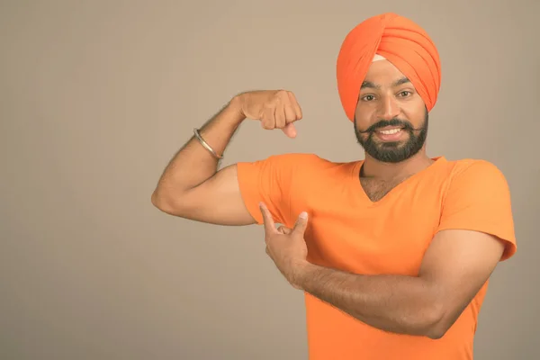 Junger schöner indischer Sikh-Mann mit Turban vor grauem Hintergrund — Stockfoto